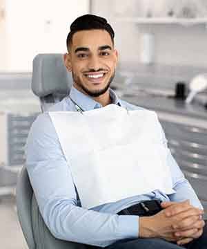 Man sitting in dental chair with hands folded