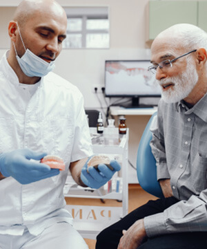 A handsome older man talking to his dentist about dentures