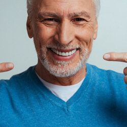 An older man pointing to his new dentures