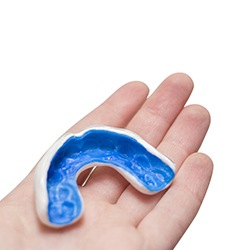 A hand holding a blue and white mouthguard