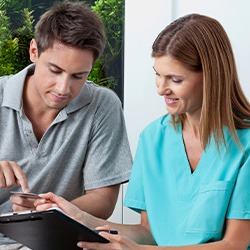 A young man paying the cost of wisdom tooth extractions