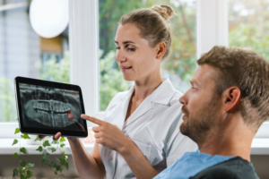 Dentist showing patient his X-ray and pointing out impacted wisdom teeth